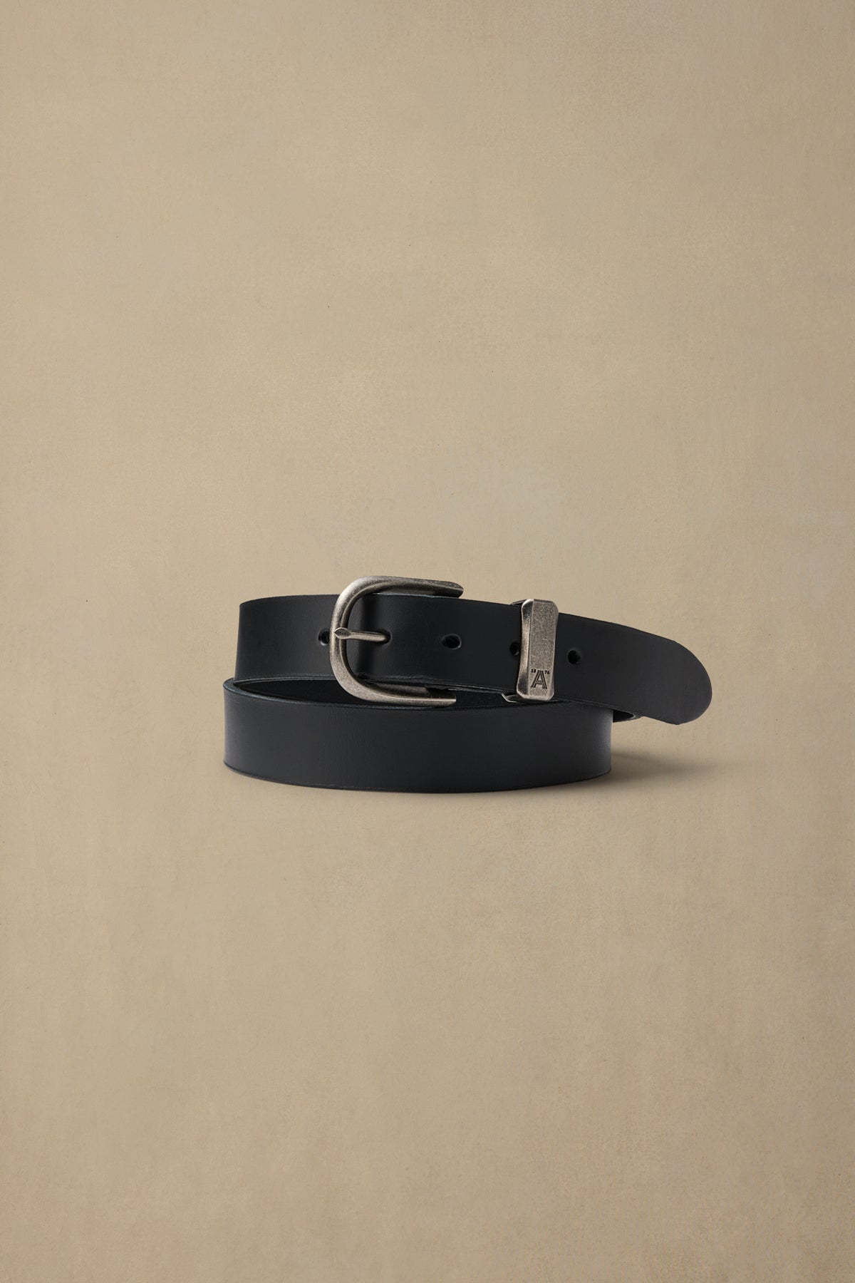 Black leather belt with silver pewter buckle and nameplate on beige background