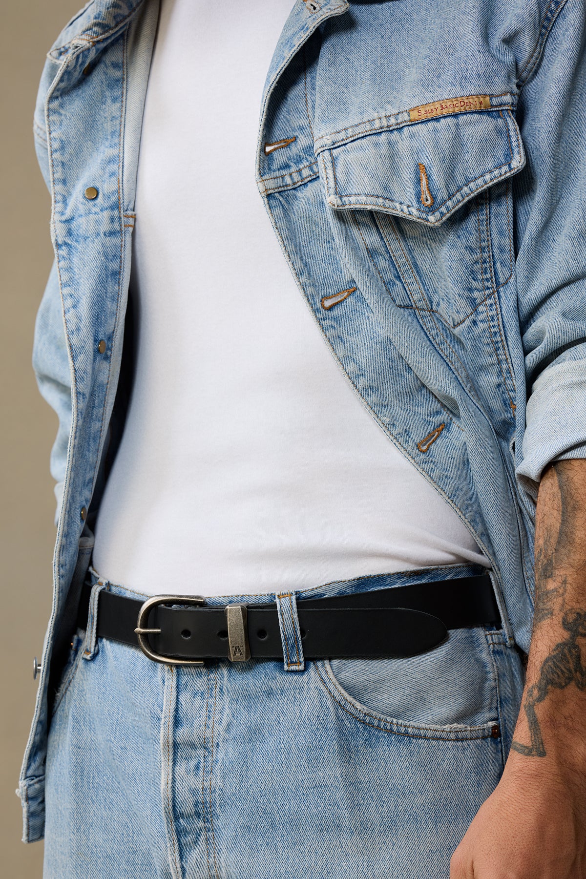 Black leather belt with silver buckle worn with light blue denim jacket and white shirt