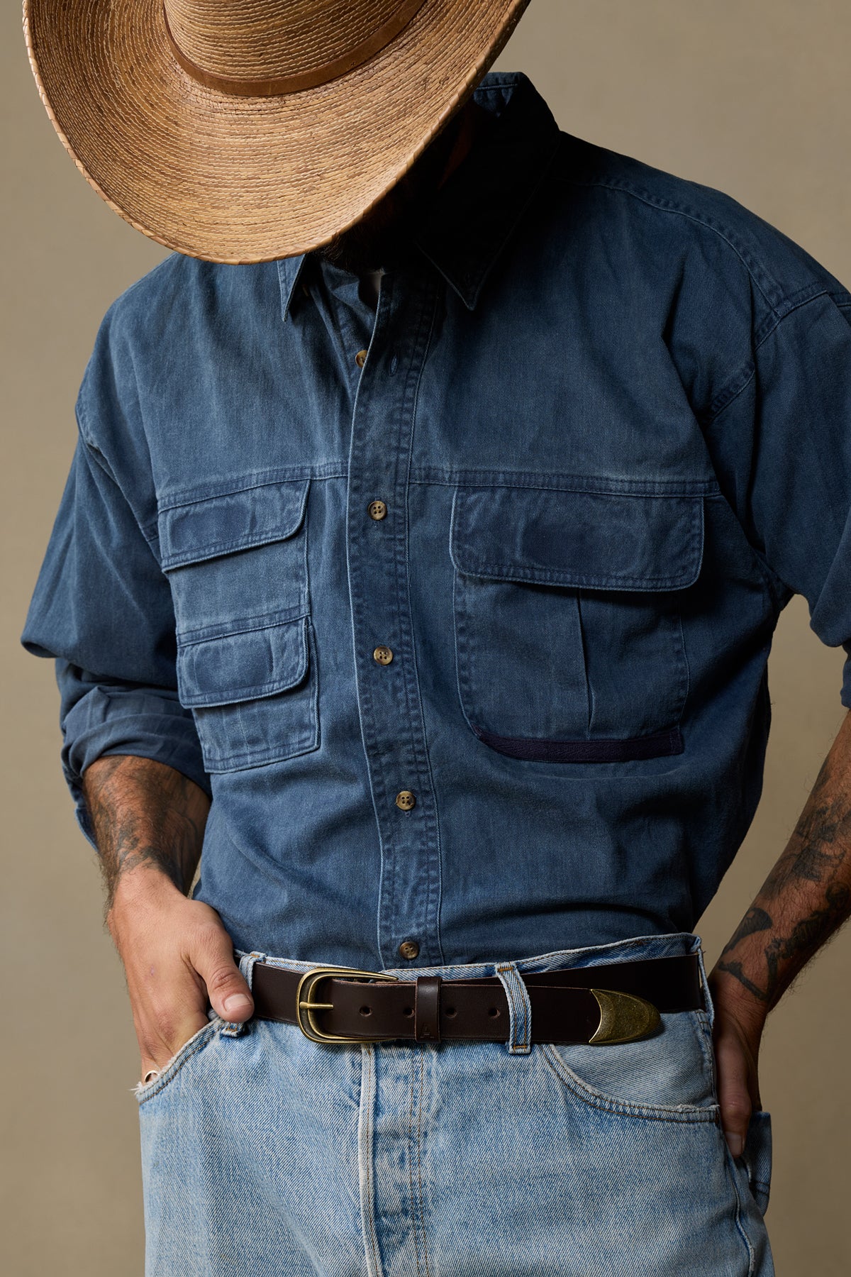 Chocolate brown leather belt with brass buckle worn with denim shirt and jeans, styled with cowboy hat