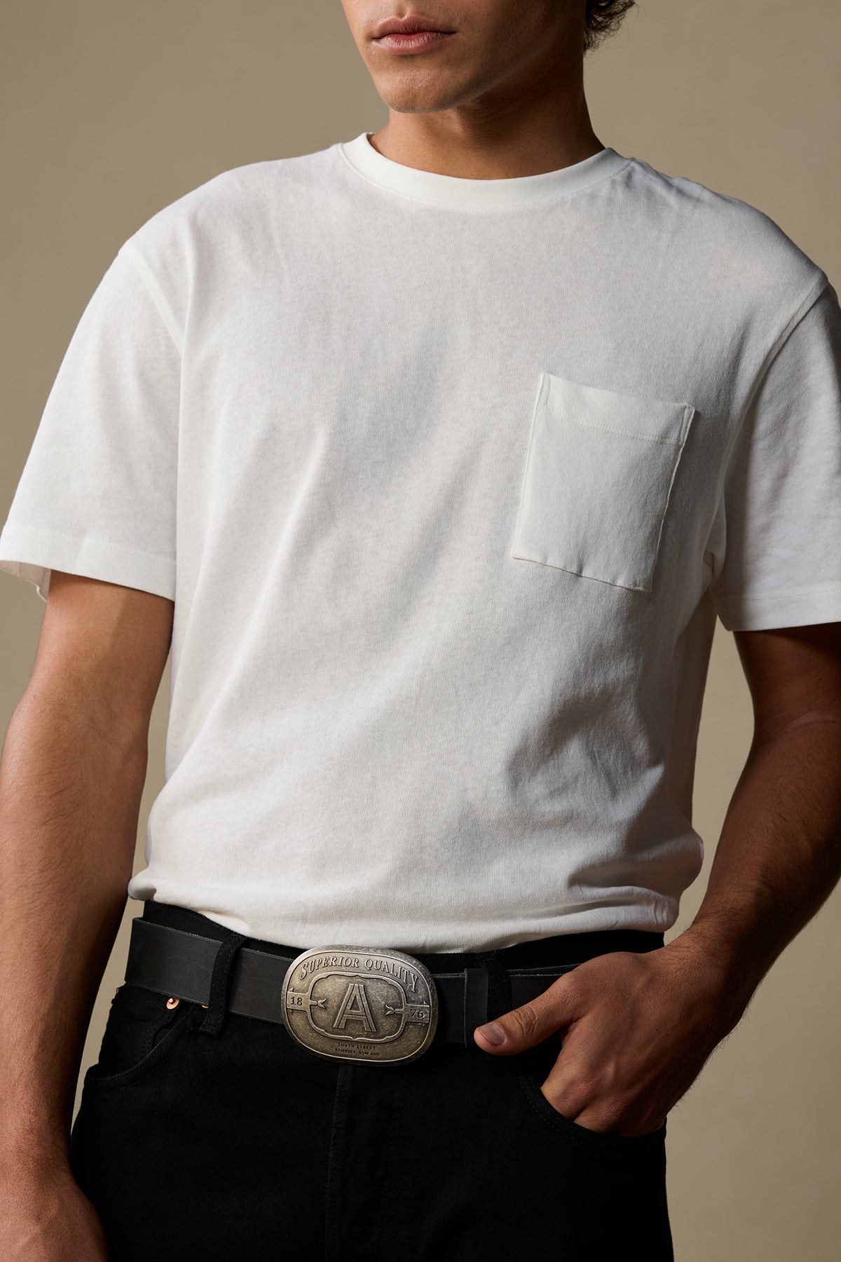 Black leather belt with silver buckle worn with white pocket tee and black pants