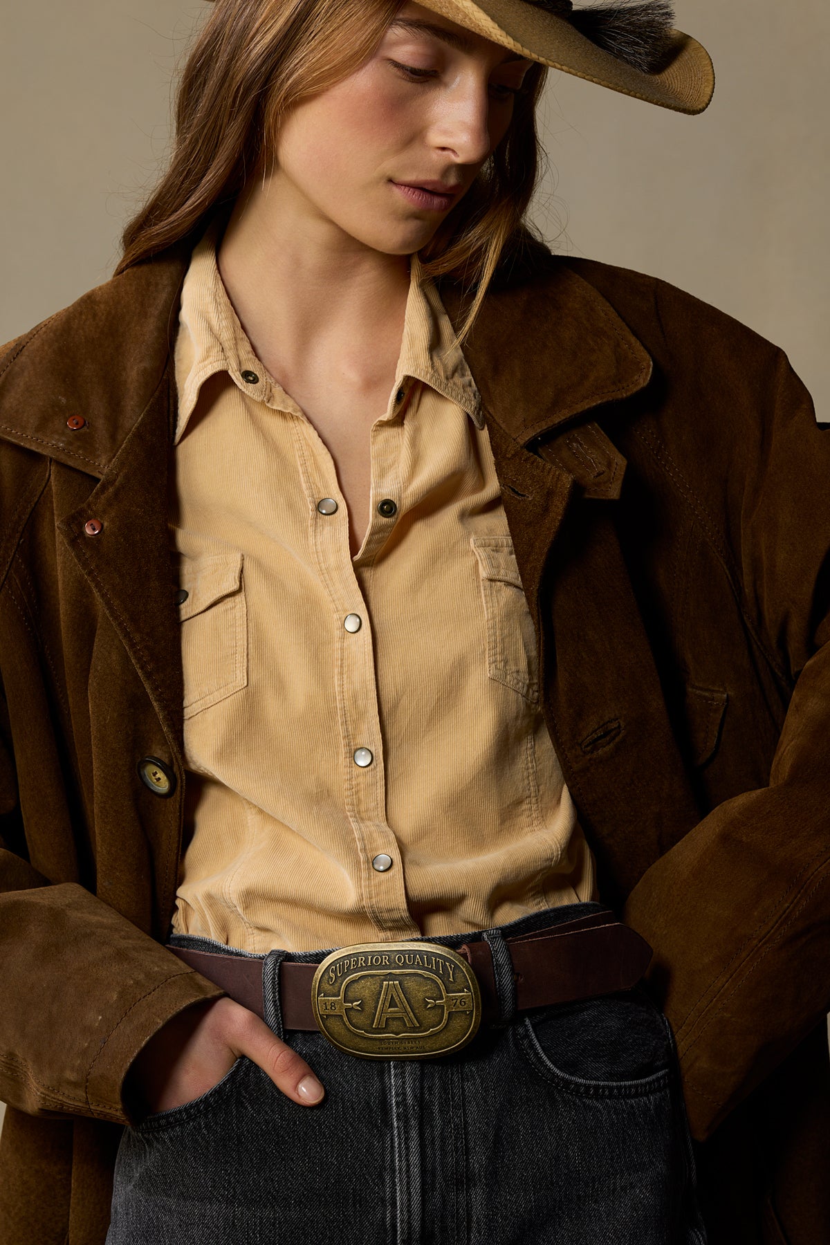 Chocolate brown leather belt with brass "A" buckle worn with tan corduroy shirt and brown jacket