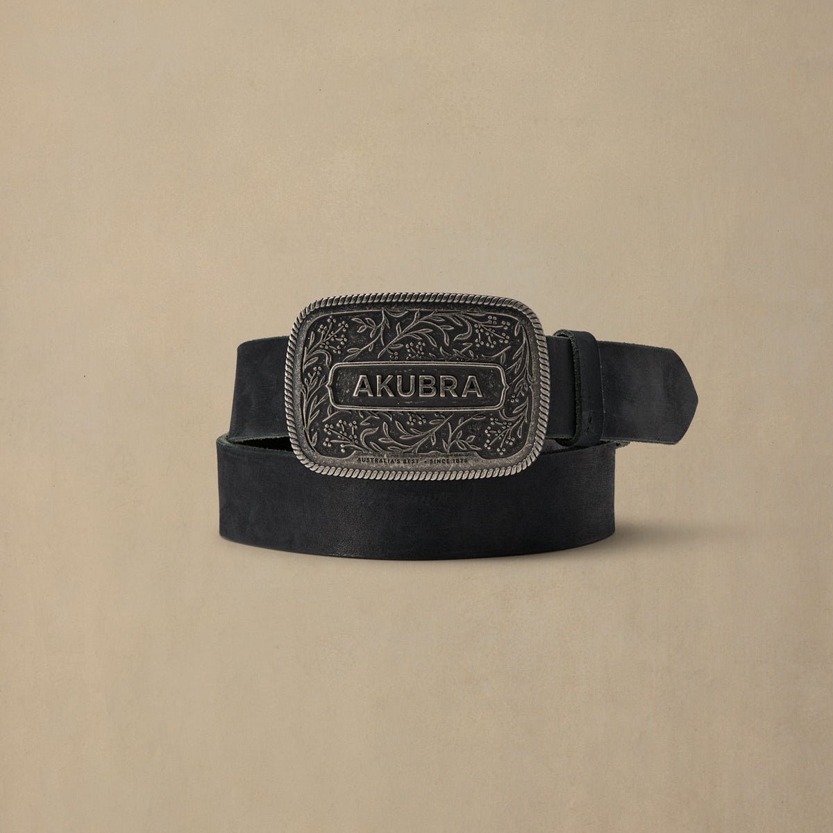 Black leather belt with ornate pewter buckle featuring AKUBRA branding and decorative floral pattern, displayed on neutral background
