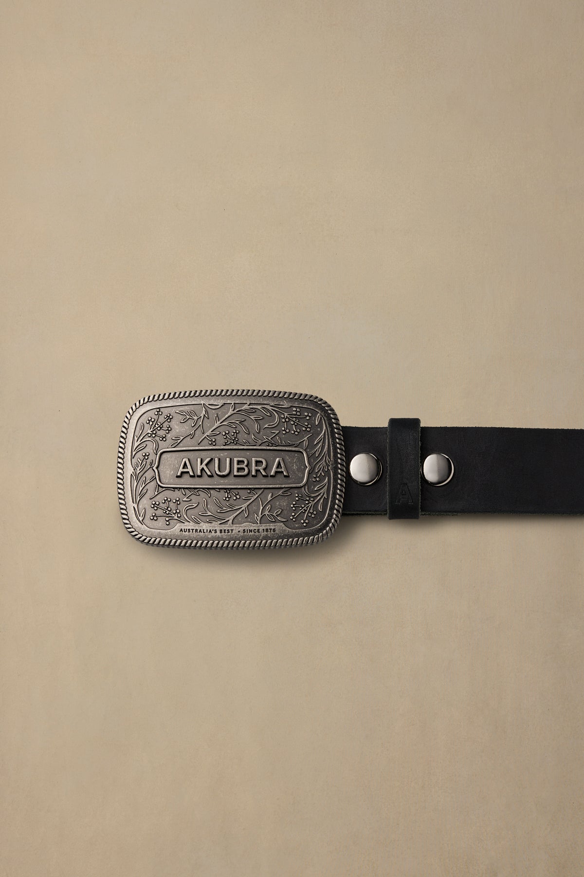 Akubra Legends black leather belt with ornate silver pewter buckle featuring floral engraving on cream background