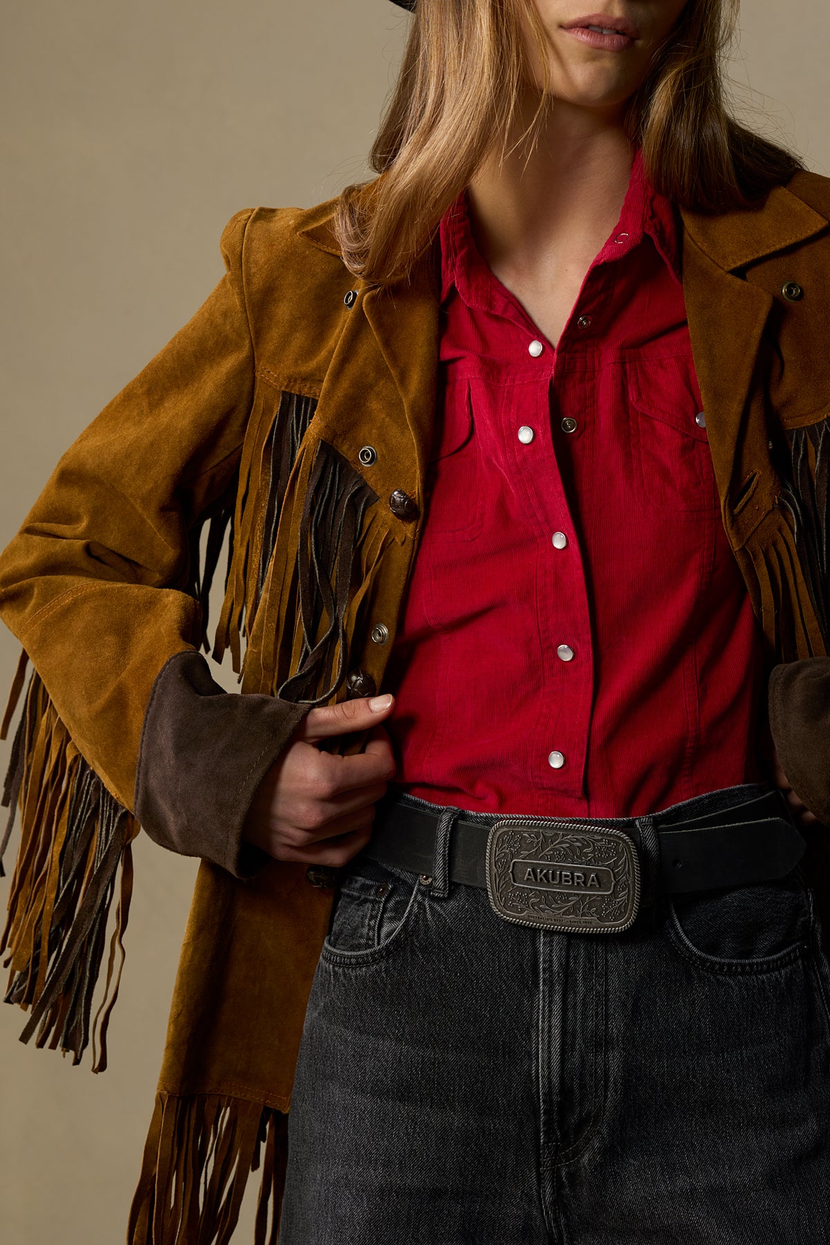 Black leather belt with ornate pewter buckle worn with red shirt and tan fringe jacket