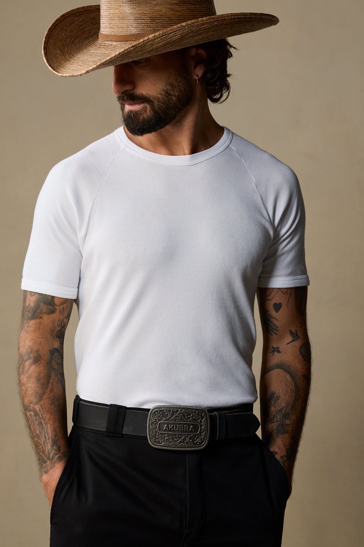 Black leather belt with ornate pewter buckle worn with white tee and cowboy hat
